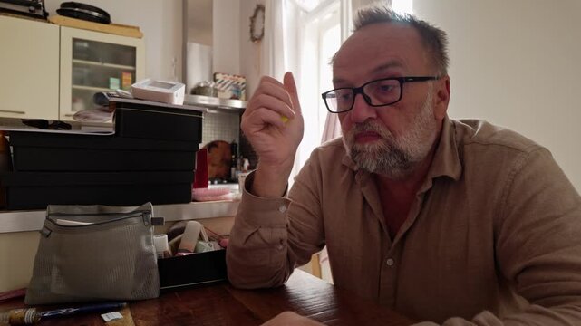 Medium shot of stressed man working online from home while squeezing a soft rubber ball, evoking work pressure, concentration, relaxation and tactile coping.