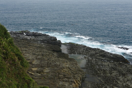 Ocean waves crash against the rocky coastal shore.