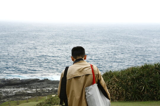 A man looks out at the ocean from the coastline.