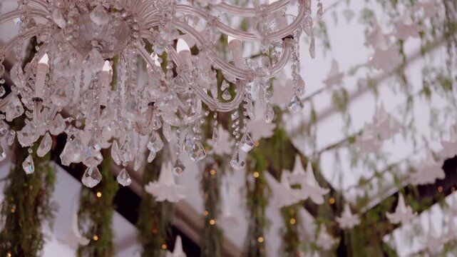 Crystal chandelier details hanging among green foliage and white paper doves creating a romantic ambiance for a special event