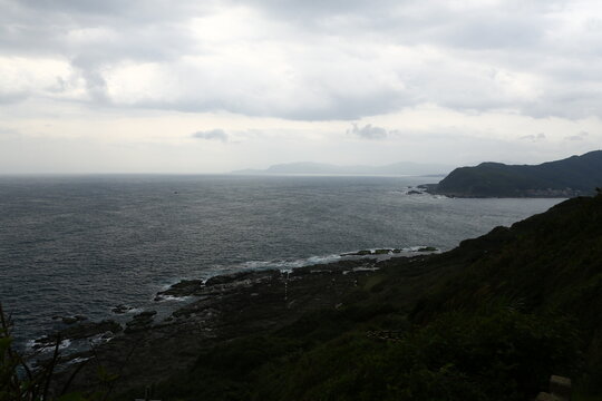 Dark clouds hang over the ocean and coastal mountains.