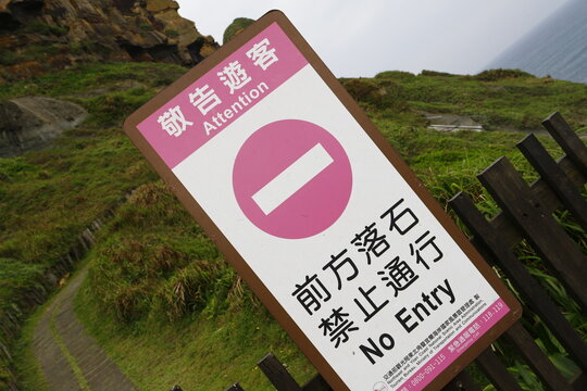 A warning sign prohibits entry due to rockfall risk along the coastal path.