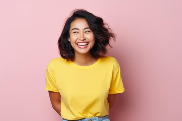 Fototapeta premium Young asian woman smiling broadly, expressing joy and positive emotions on a pink background