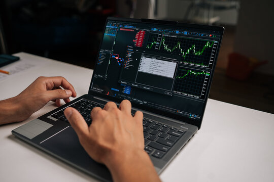 Person trading online, monitoring stock market charts and financial data on laptop computer, analyzing investments and making decisions for wealth management using digital technology at home.
