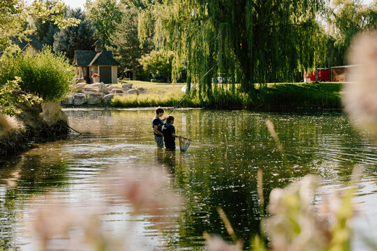 Two young boys fishing together in a pond