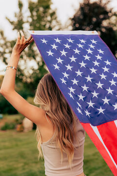 Young woman from behind holding an American flag