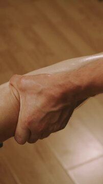 closeup of hands rubbing lotion into ankle and lower leg with steady pressure on warm wooden floor indoors aid