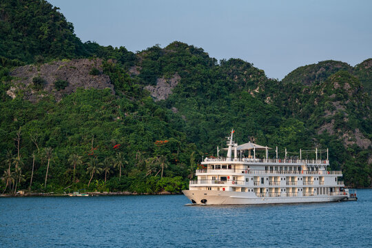 A luxury tour boat cruises through a scenic tropical bay