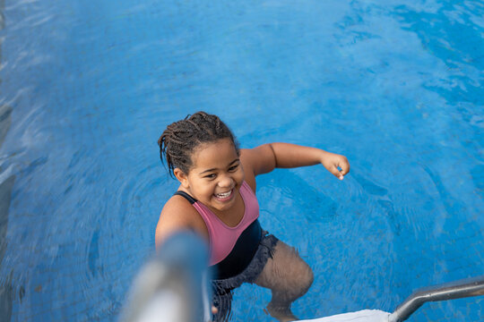 Happy young girl with braids in a swimming pool