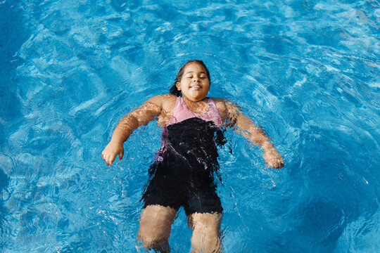 Young girl floating peacefully on her back in a pool
