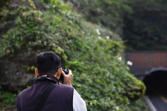 A photographer takes pictures of the surrounding mountain landscape.