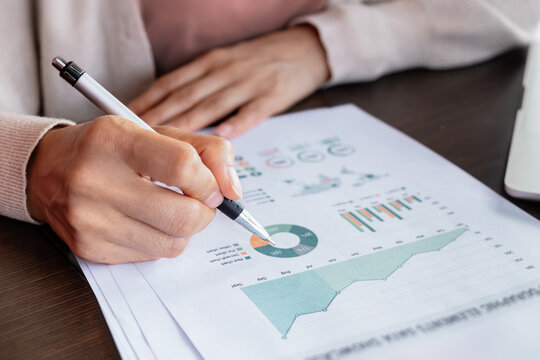 Close-up of a hand reviewing financial charts and graphs on a business report. Representing data analysis, planning, investment research and corporate strategy.