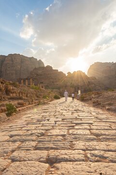 Two locals walk on Old Roman Road next to ruins of Petra, Nabataean city of Petra, near Wadi Musa, Jordan