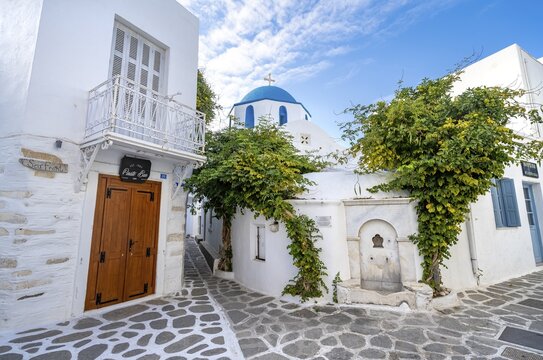 Small alley in Parikia with white houses, Mavrogeni fountain and Greek Orthodox Church with blue roof, Parikia, Paros, Cyclades, Aegean Sea, Greece