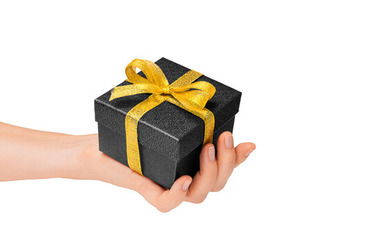 Female hand holds black gift box with gold ribbon isolated on transparent background for Black Friday sale discounts promotions and holiday offers