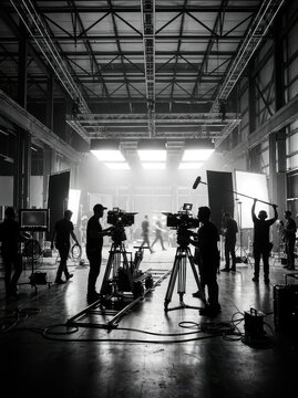Professional Film Crew Working on a Movie Set in a Large Industrial Studio, Black and White Cinematic Production Scene
