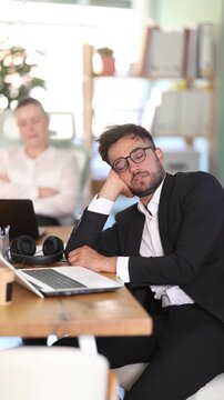 Office employees got tired and fell asleep during a break at work. Man and woman sleeping near laptop in office interior . High quality 4k footage