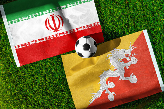 Iran vs. Bhutan football match. National flags on green grass with soccer ball in the middle. Football background for international match.