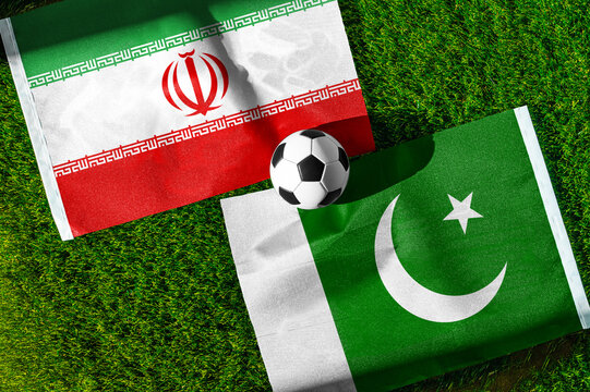 Iran vs. Pakistan football match. National flags on green grass with soccer ball in the middle. Football background for international match.