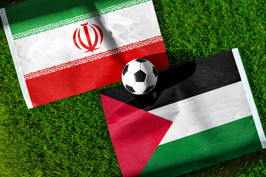 Iran vs. Palestine football match. National flags on green grass with soccer ball in the middle. Football background for international match.