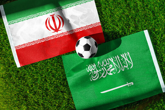 Iran vs. Saudi Arabia football match. National flags on green grass with soccer ball in the middle. Football background for international match.