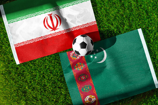 Iran vs. Turkmenistan football match. National flags on green grass with soccer ball in the middle. Football background for international match.