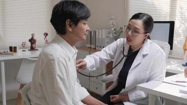 Asian Female Doctor Using Stethoscope to Examine Male Patient's Heart Beat in Medical Clinic