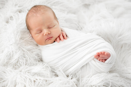 Peaceful infant resting comfortably on a fluffy white rug during the daytime