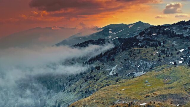 Cinematic mountain range with rolling fog during a vibrant orange