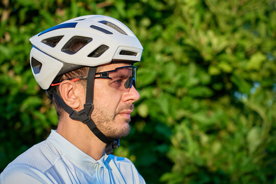 Close-up portrait of a male cyclist wearing a helmet and sports glasses outdoors