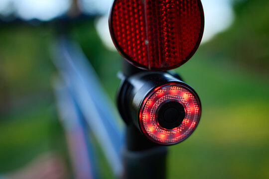 Close-up of a red rear light and reflector on a bicycle.