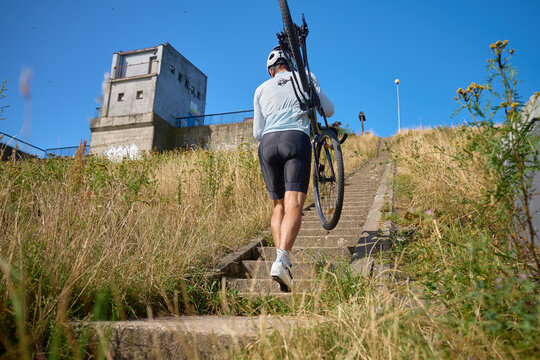 Cyclist carrying bicycle up stairs outdoors