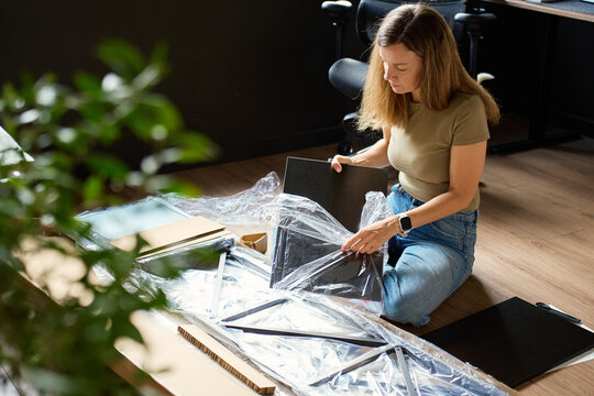Woman unpacking shelf parts from furniture package at home