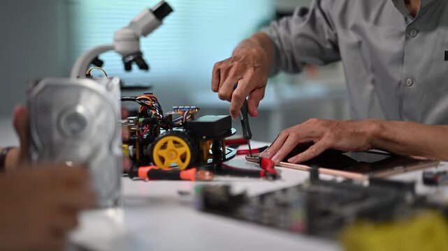 Technician Working on Electronic Device with Testing Equipment in Laboratory
