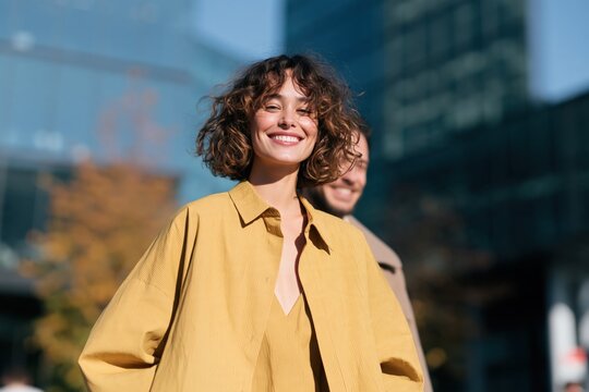 Smiling woman in yellow shirt urban lifestyle portrait for banner and background design showing confident happy professional in city setting