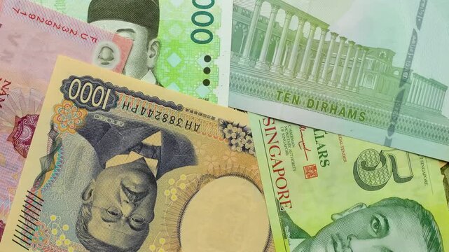 Rotating close-up of assorted world banknotes including Japanese yen, Vietnamese dong, Singapore dollars and UAE dirham