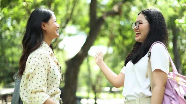 Two university students share bond of affection chatting and joking in high good mood they hold hands with a sense of care before heading home.