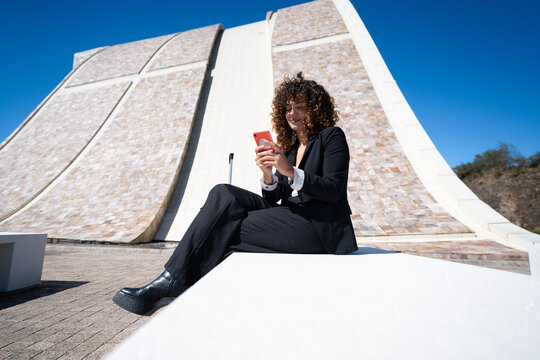 Businesswoman using smartphone sitting outdoors