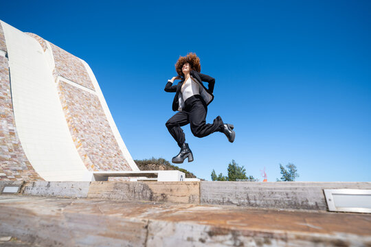 Businesswoman jumping outdoors near a modern building