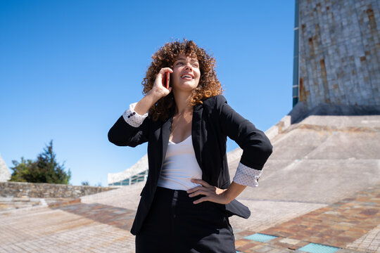 Businesswoman talking on phone outdoors near modern architecture