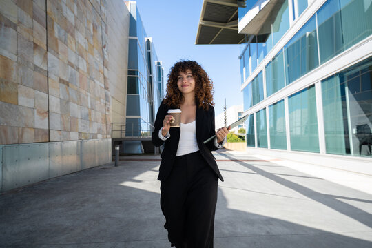 Businesswoman walking with coffee and folder