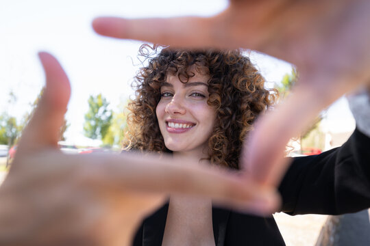 Young white woman with curly hair framing face outdoors