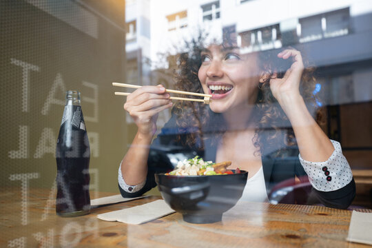 White woman eating asian food with chopsticks