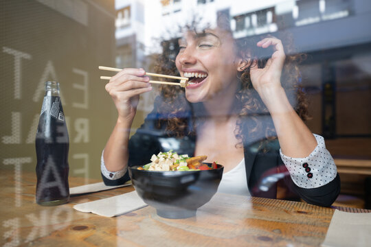 White woman enjoying meal with chopsticks inside restaurant in Spain