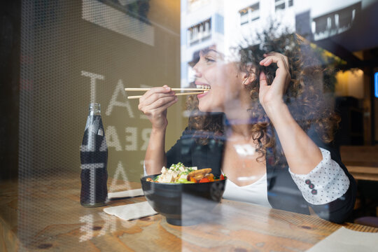 Businesswoman eating lunch with chopsticks inside restaurant in Spain