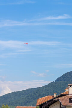 Bansko, Bulgaria, red emergency medical service helicopter flying over town, green Pirin mountains