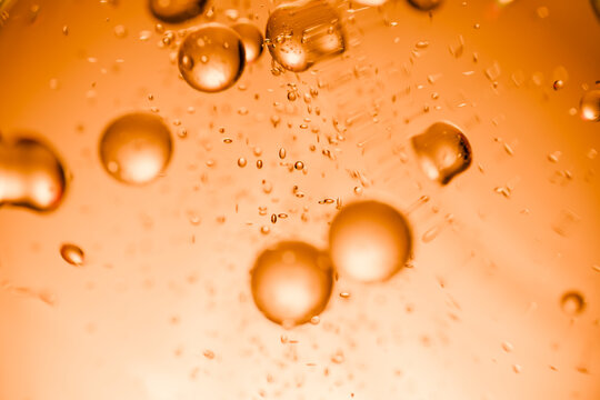 Orange liquid bubbles suspended in bright abstract macro background