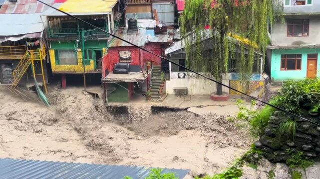 View of a river overflowing violently between houses due to heavy flooding caused by monsoon rains in India. A natural disaster resulting from climate change.