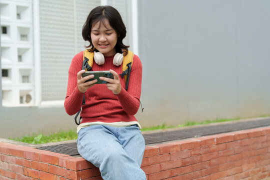 Young asian woman gaming on smartphone outdoors