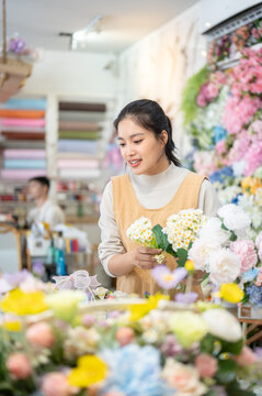 florist shop woman in apron doing daisy bouquet arrangement asian retail store business work selection colorful